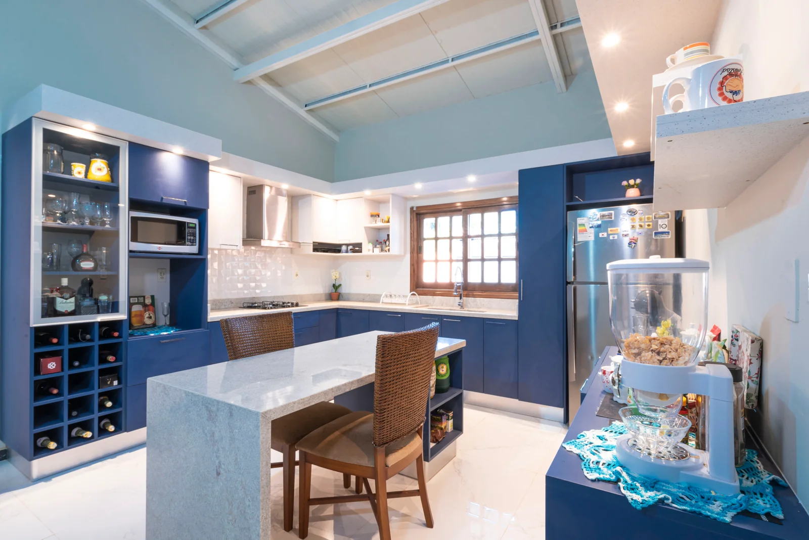 Cocina Areguá renovada, con mobiliario azul y blanco, vitrina y barra central