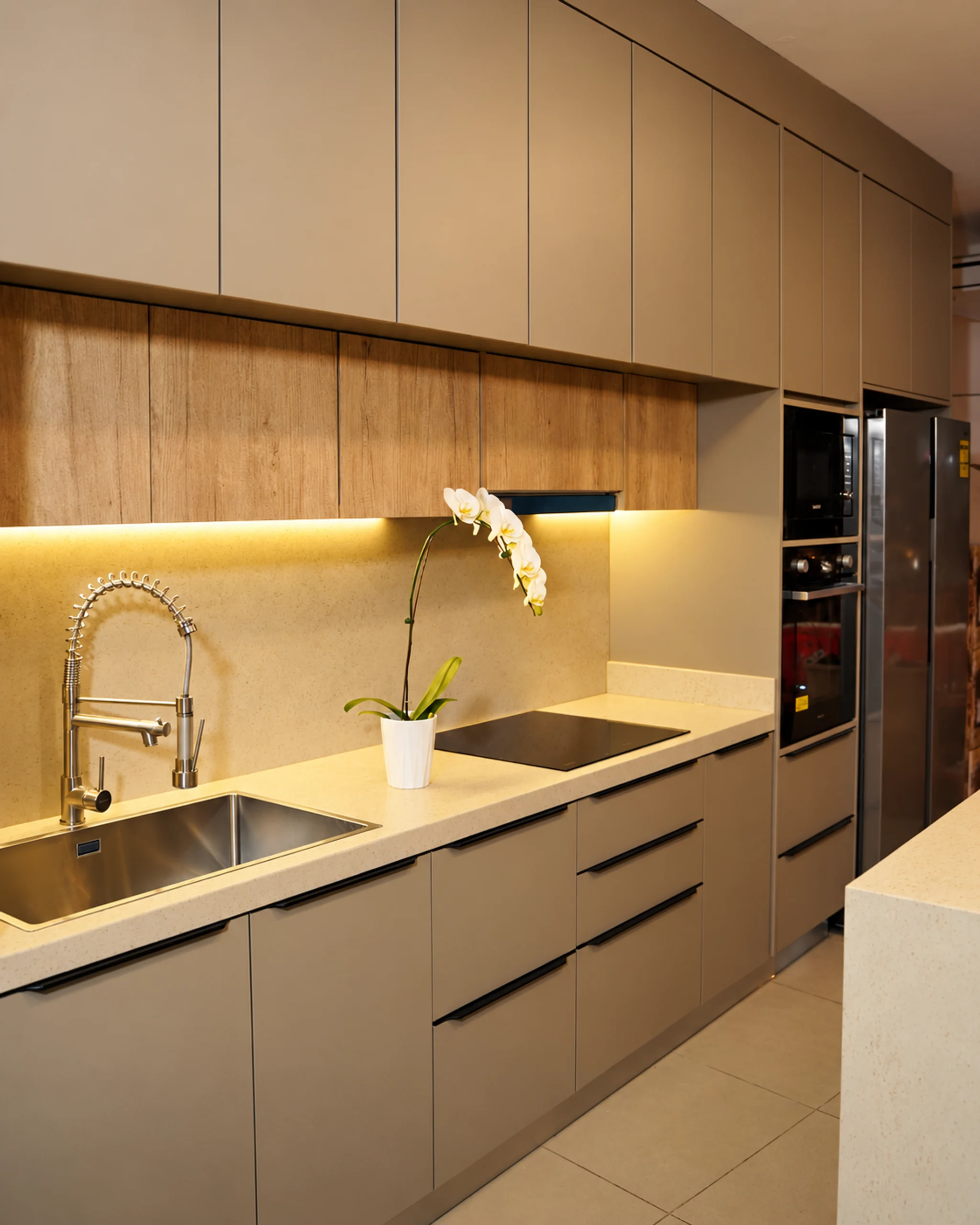 Detalle de cocina Amoblarte con mesada clara, orquídea e iluminación cálida